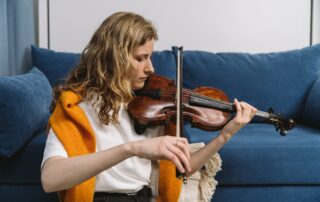 a woman playing violin in front of a blue couch