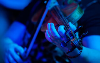 professional violinist performing on stage under blue lights
