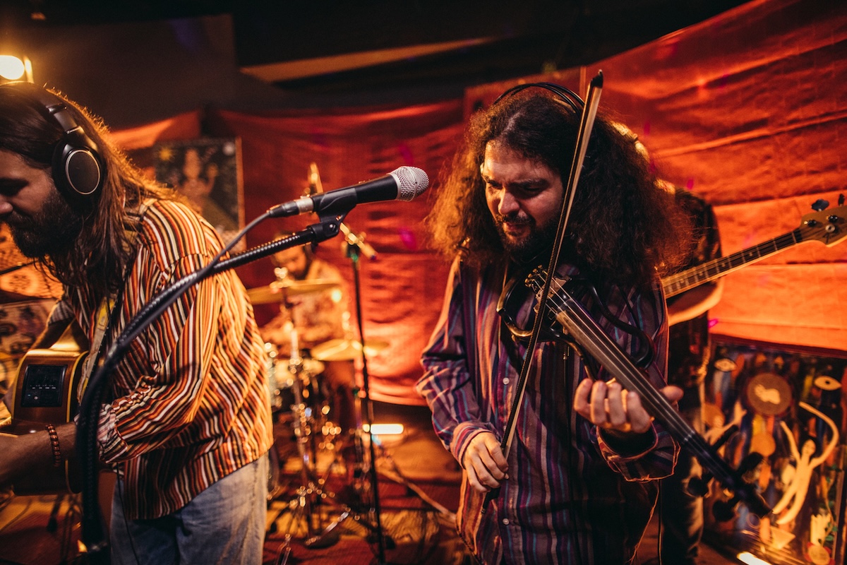 Group of men, musicians performing on stage together, including a man with an electric violin