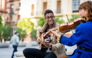 male guitarist and female violinist busking together on the street