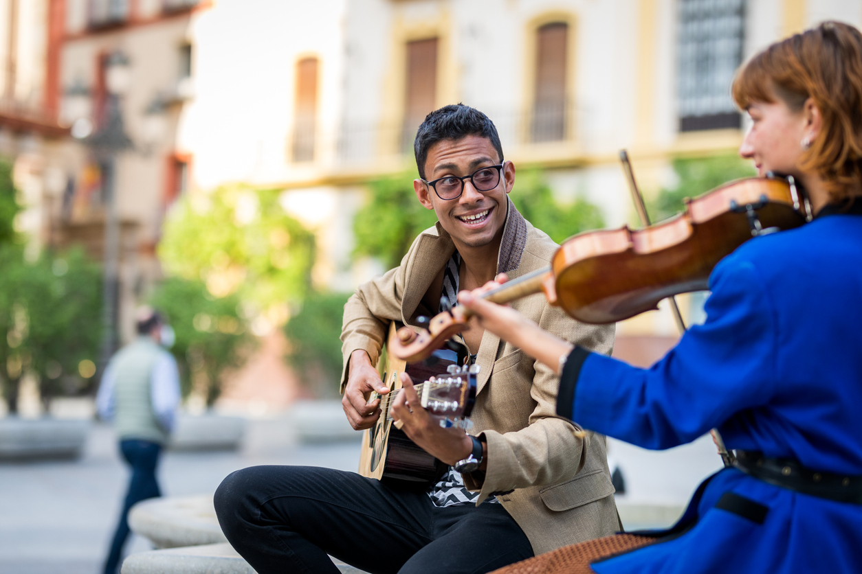 male guitarist and female violinist busking together on the street