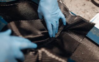carbon fiber square being held by blue gloves