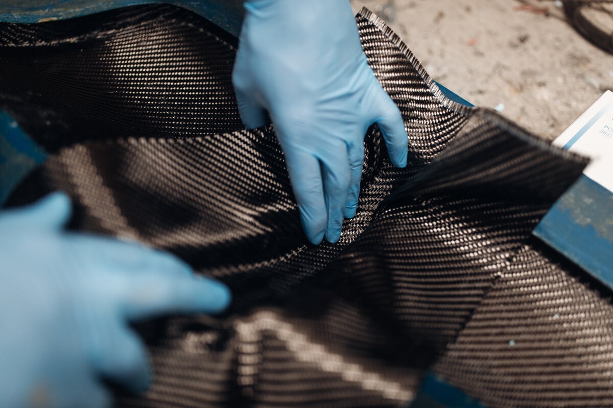 carbon fiber square being held by blue gloves