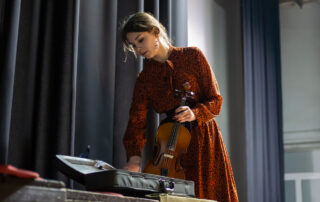 violinist removing violin from its case while backstage