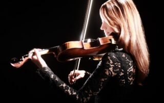 woman playing violin against black background
