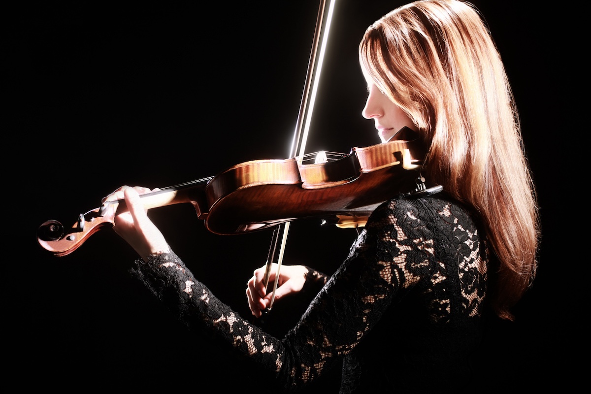woman playing violin against black background