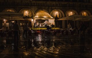 group of musician playing under awning of restaurant's awning; dark silhouettes of people listening