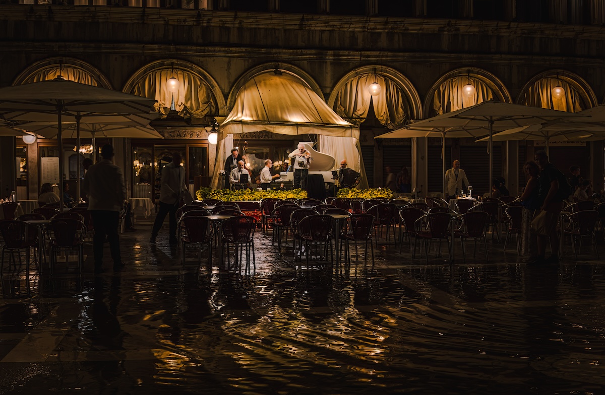group of musician playing under awning of restaurant's awning; dark silhouettes of people listening