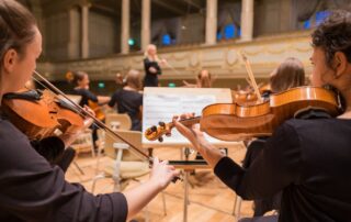 string orchestra playing in front of a conductor
