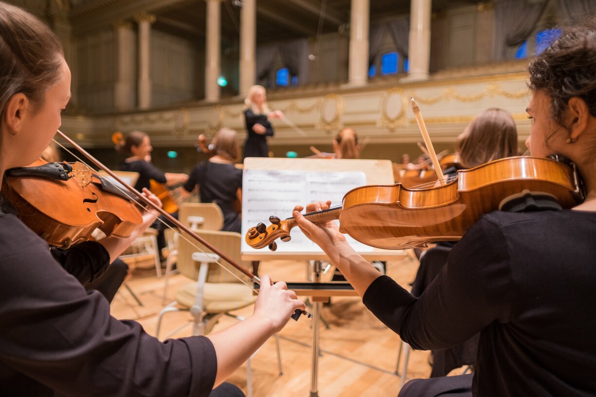 string orchestra playing in front of a conductor