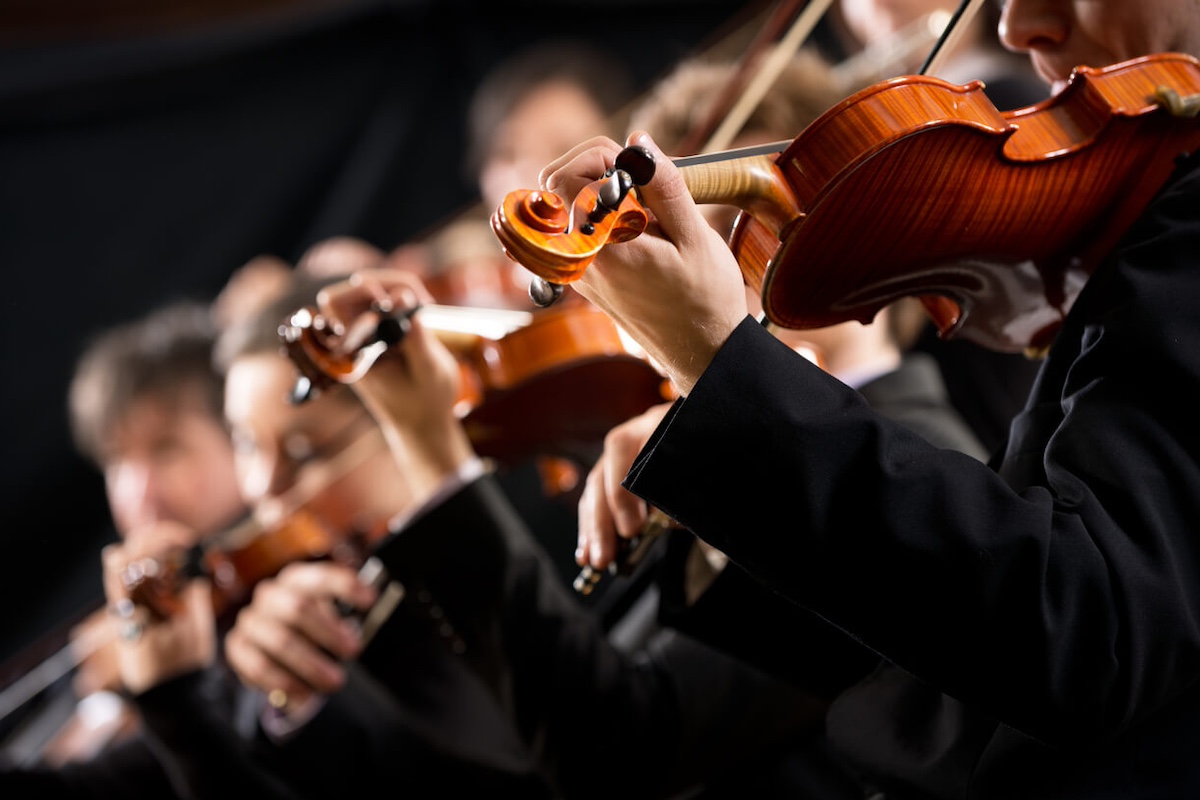 angled shot of violinsts in an orchestra with the first player being clear and those behind him blurred
